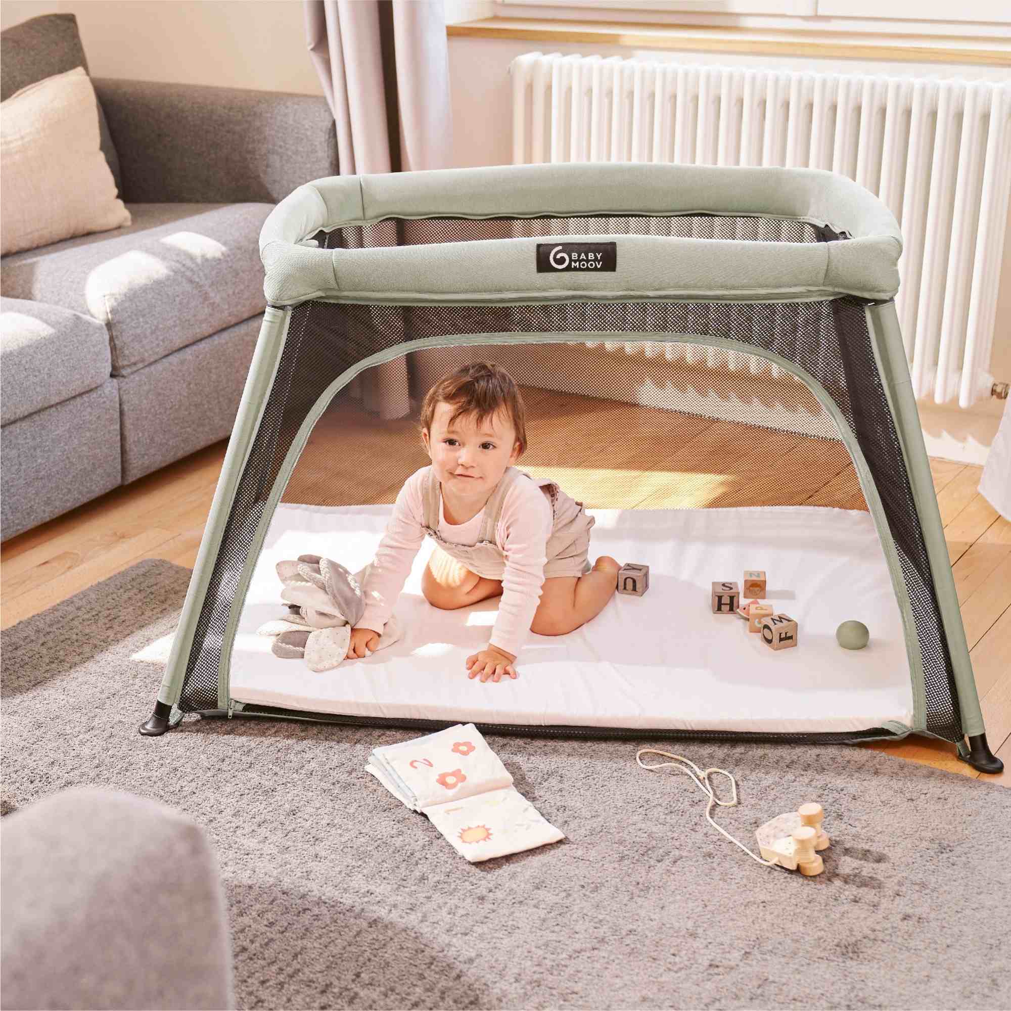 Baby playing on a portable playpen in a living room.