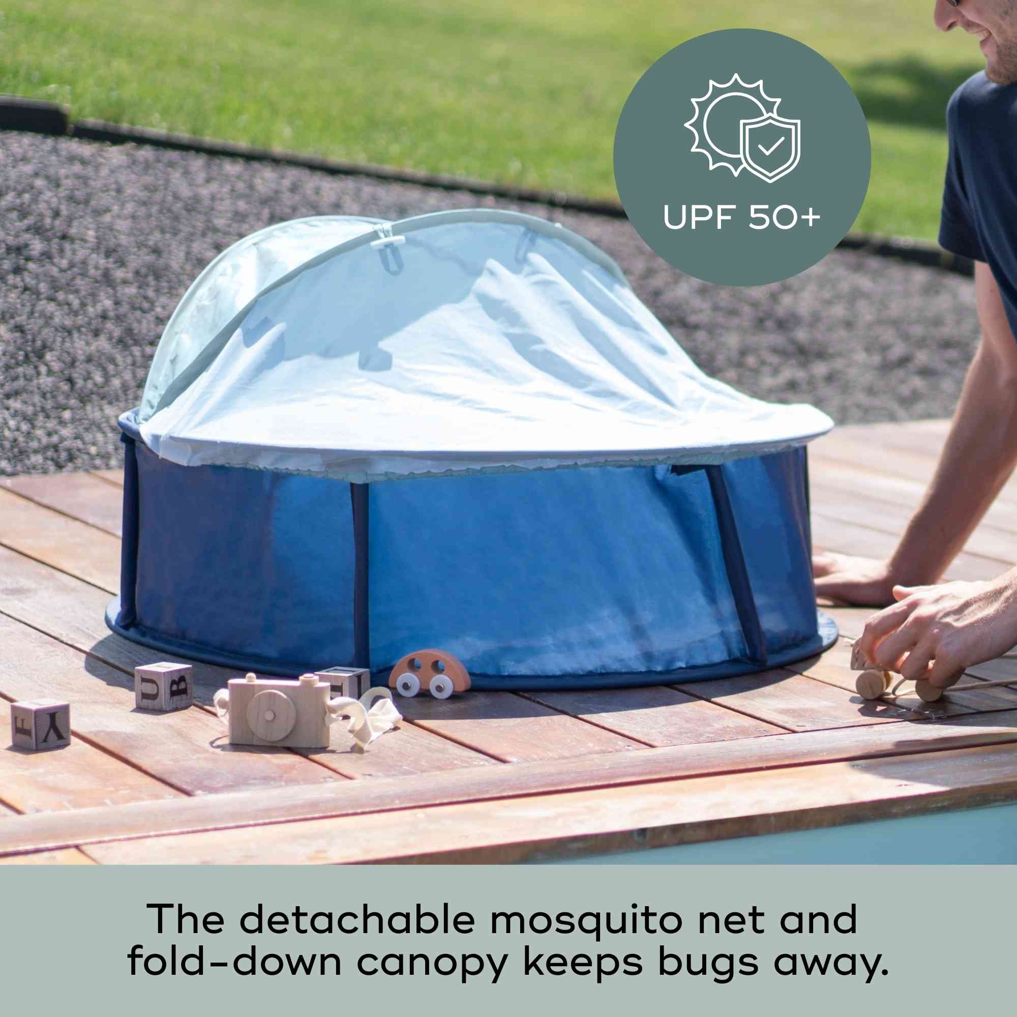 Blue baby popup tent with detachable mosquito net and fold-down canopy on a wooden deck.
